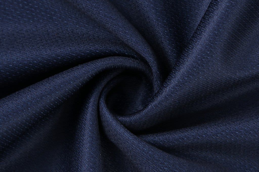 A fabric swatch in deep navy, featuring a textured pattern with a smooth, swirl design. It has a logo visible.