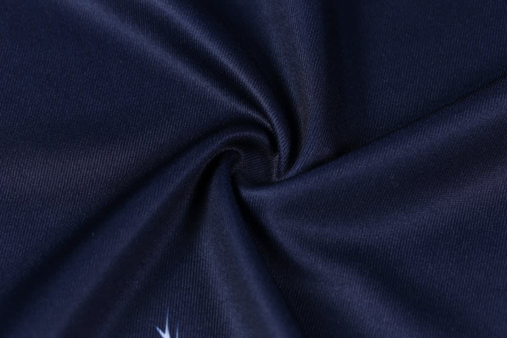 A close-up of dark navy fabric displaying a smooth texture, featuring a logo in the corner.