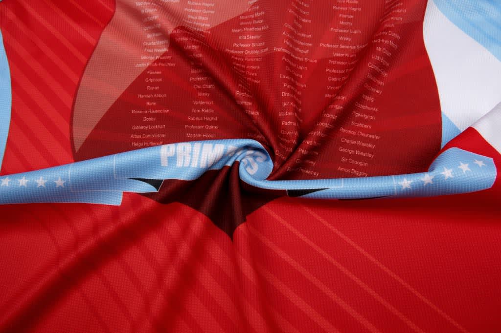 A red and blue sublimation polo featuring a textured fabric with a swirling design and a logo.