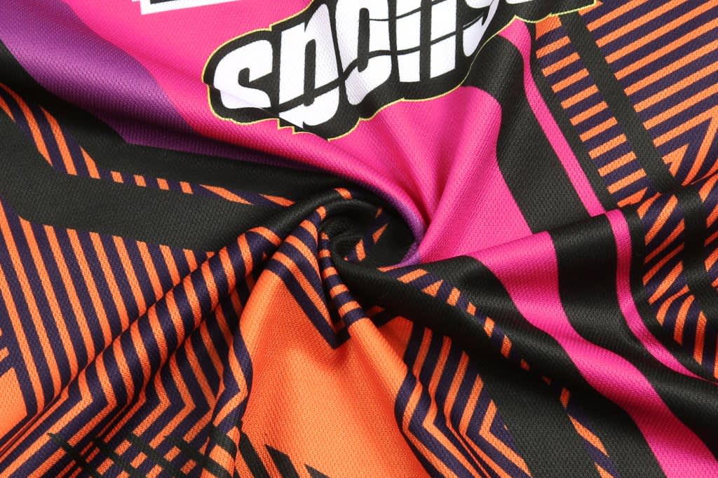 A custom BMX T-shirt featuring a vibrant design with pink, black, and orange patterns, along with branding.