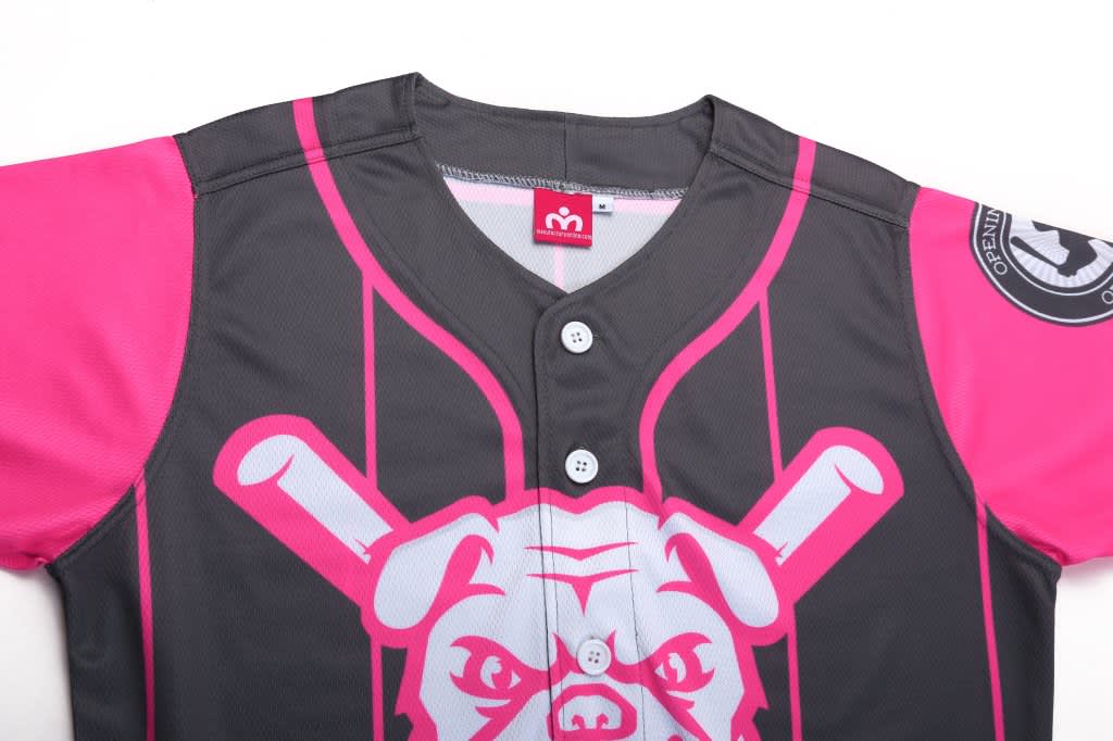 A full button baseball jersey featuring black fabric with bright pink sleeves and a graphic design, including a logo.