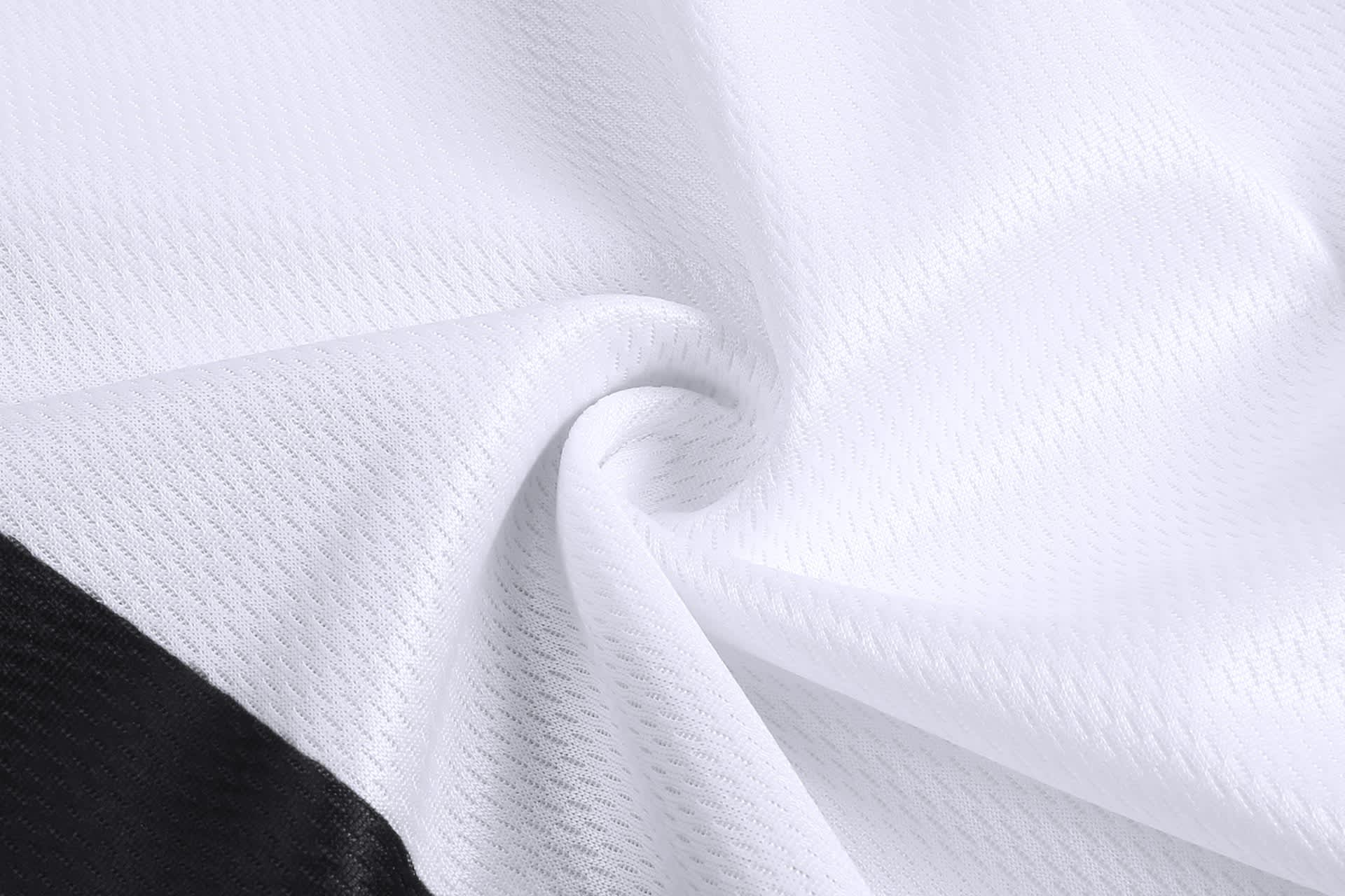 A close-up of textured fabric featuring white material with black accents, suitable for baseball training pants.
