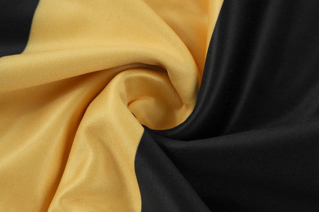 A close-up of fabric featuring a swirl of black and gold colours, highlighting a soft texture.