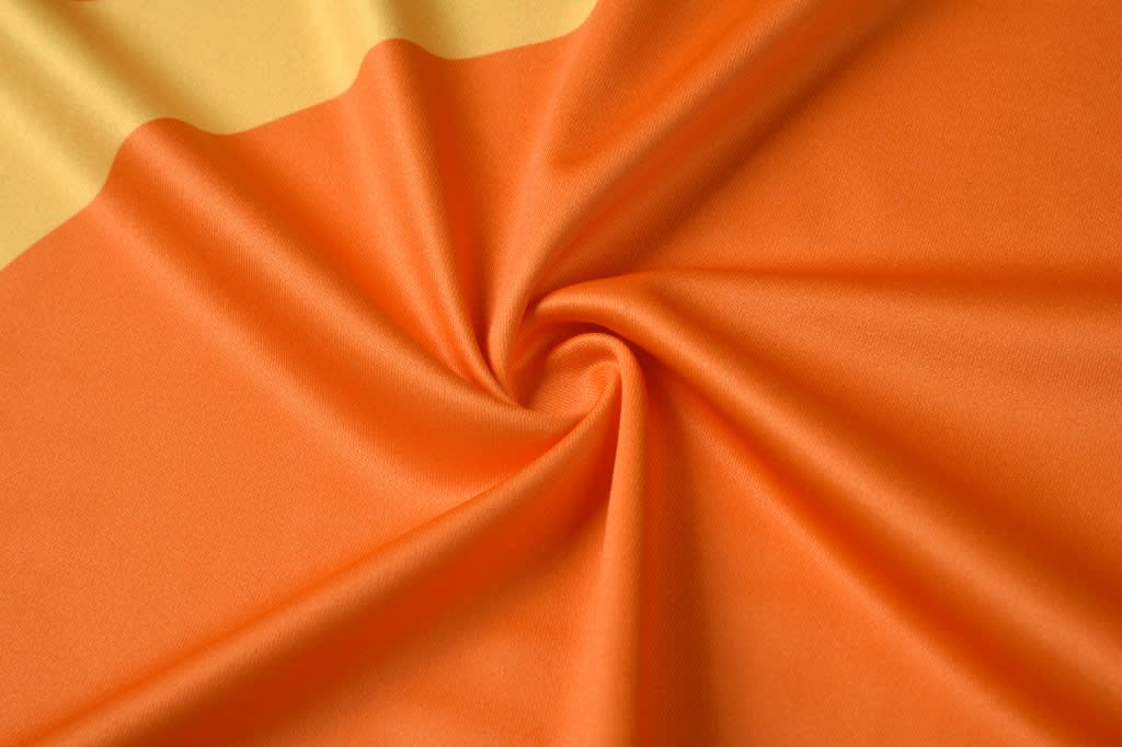 An orange fabric with a smooth texture, featuring a swirl pattern.