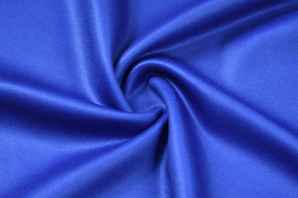 A smooth, vibrant blue fabric featuring a subtle sheen, showcasing the texture and drape of the material.
