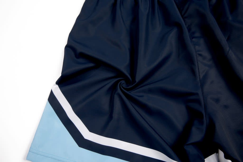 Navy blue woven school shorts with a light blue and white stripe detail. The shorts have a logo on them.