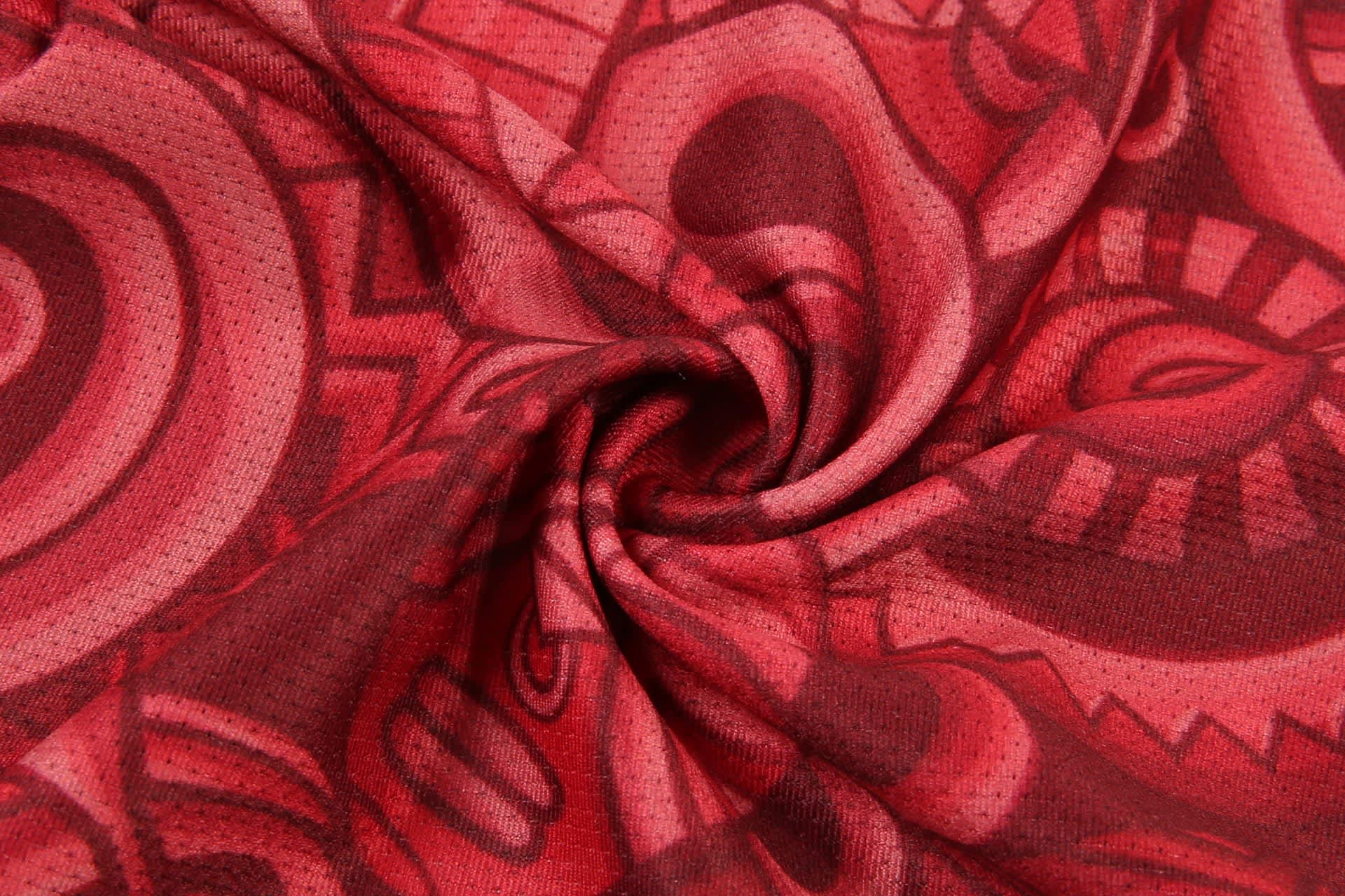 A red women's basketball uniform singlet featuring a vibrant, abstract pattern and a logo.