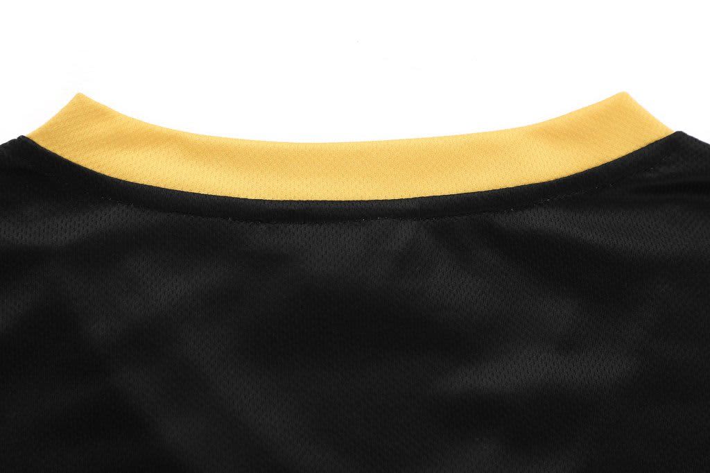 A black V-neck tee with a yellow collar featuring a logo on the back.