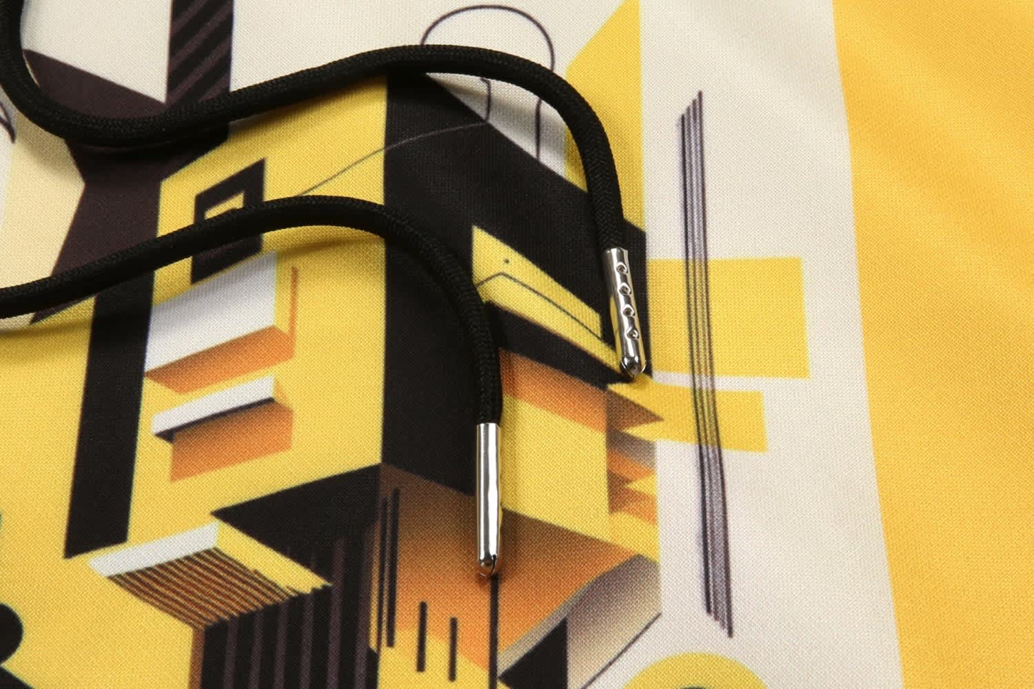 A close-up of a patterned fabric featuring yellow and black geometric designs, with black drawstrings.