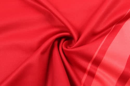 A vibrant red fabric, showcasing a smooth texture and lightweight material, ideal for sports uniforms.