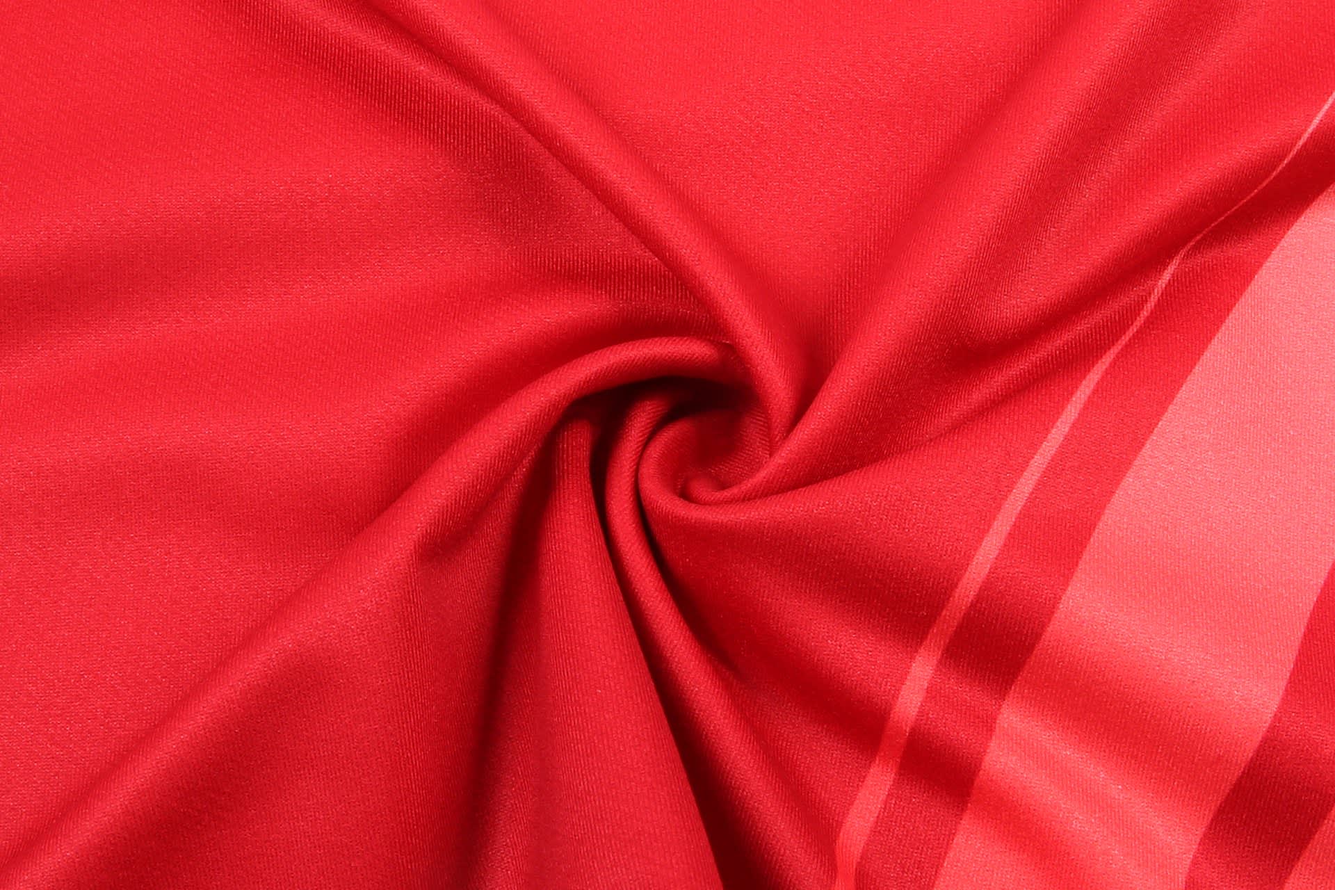 A red fabric swirled in a circular pattern, showcasing a smooth texture and slight sheen.