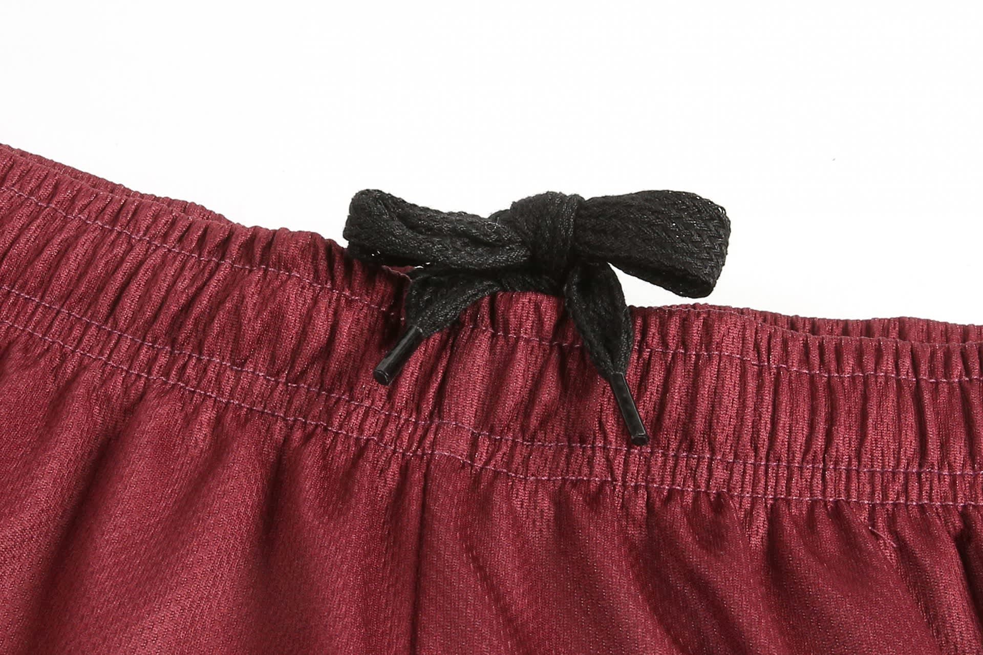 ABORIGINAL SHORTS in maroon with a black drawstring at the waistband, featuring a logo on the fabric.