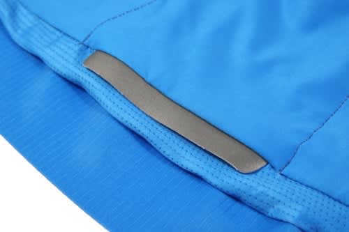 A close-up of a blue sports jersey featuring a silver logo patch on the hem. The fabric is textured and breathable.