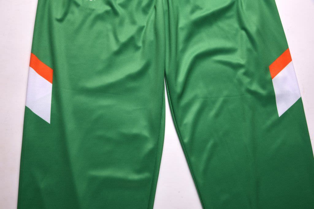 Green sports pants featuring orange and white accents, with a logo on the fabric.