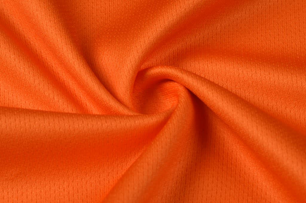 An orange fabric displayed in a swirling pattern, showcasing its smooth texture.