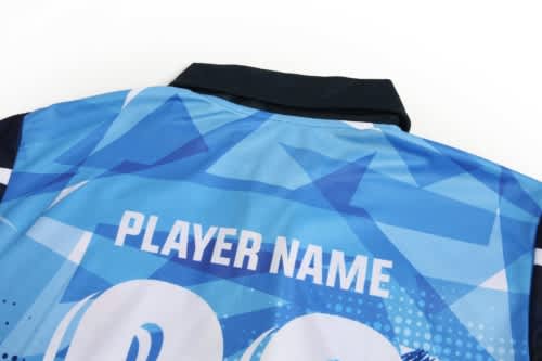 A blue cricket jersey featuring a geometric pattern and a collar, with a space for a player's name.