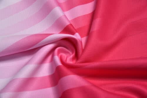 A close-up of fabric featuring pink and light pink stripes, designed for sports uniforms. The fabric is smooth and stretchy.