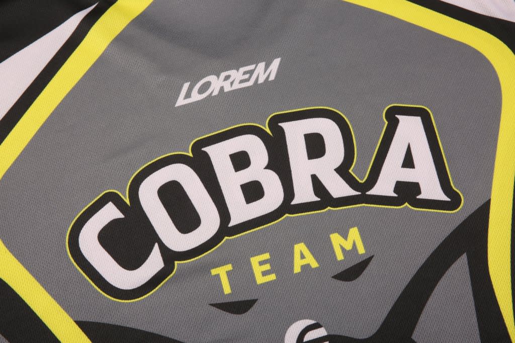 A jersey featuring a grey design with yellow accents, displaying the word "COBRA" prominently, along with a logo.