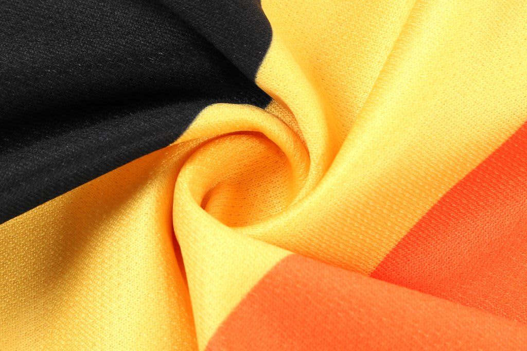 A close-up of a fabric featuring black, gold, and red colours, arranged in a swirling pattern.
