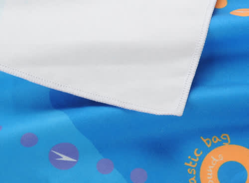 A beach towel featuring a double-faced pile, with vibrant blue and white colours and abstract designs.