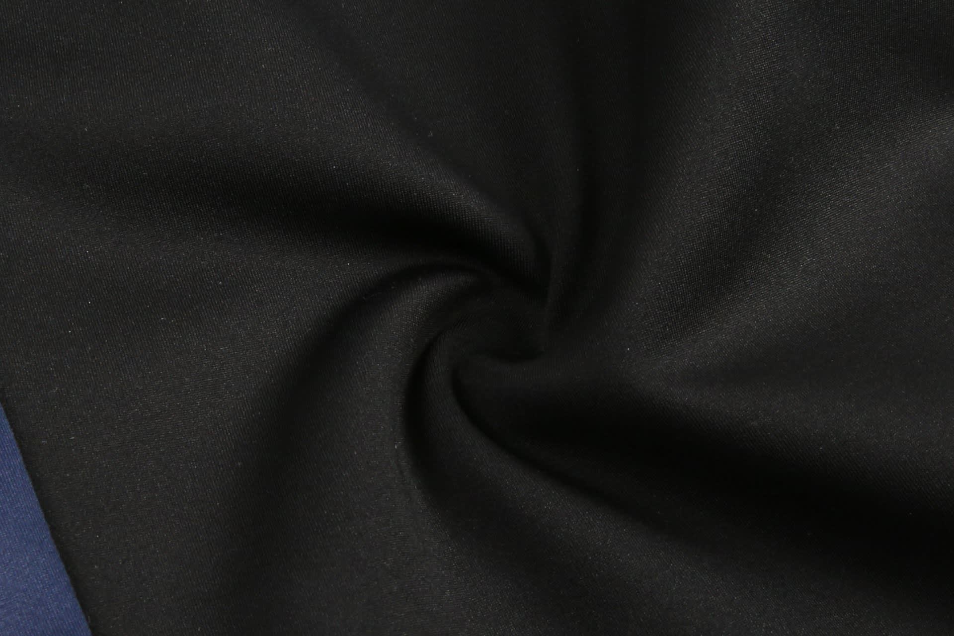 A close-up of black fabric with a smooth texture, featuring a swirl pattern. The image also includes a hint of navy.