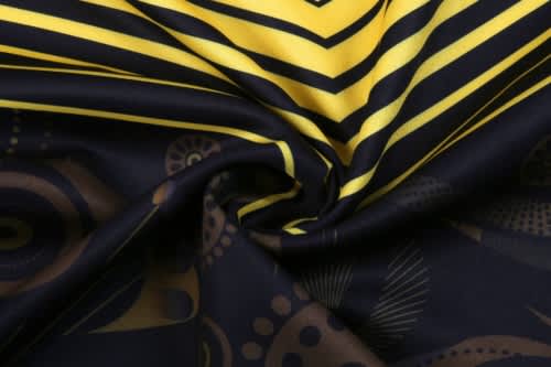 A close-up of fabric featuring bold yellow and black patterns, designed for the "COTTON PRINTING ABORIGINAL HOODIE."