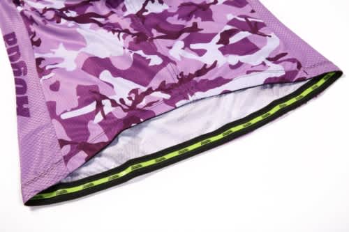 A purple camouflage sports jersey featuring a mesh design and an inner lining with a green detail, along with a logo.