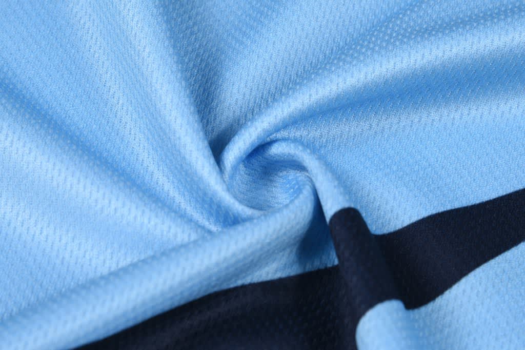 A light blue fabric with a smooth texture, featuring a dark navy horizontal stripe. The material appears breathable.