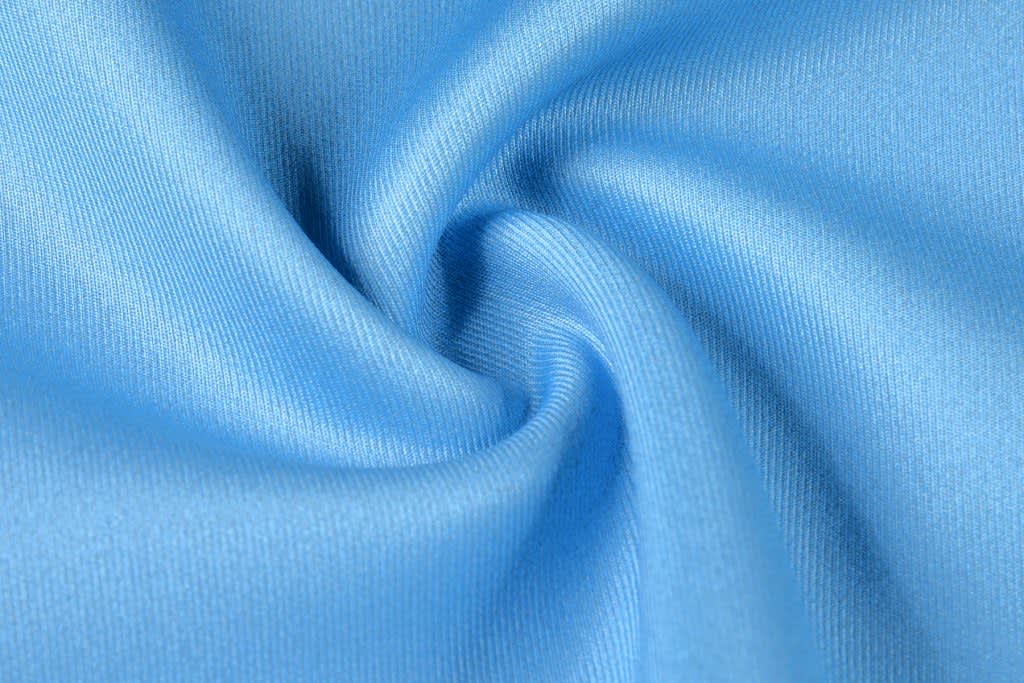 A lightweight, smooth fabric in a light blue shade with a subtle sheen, featuring a swirling texture.