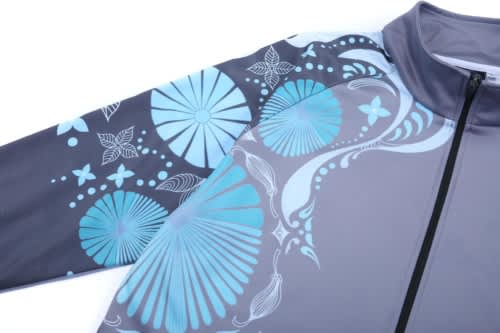A school wear jacket in grey with blue floral and abstract patterns, featuring a zip closure and a high collar.