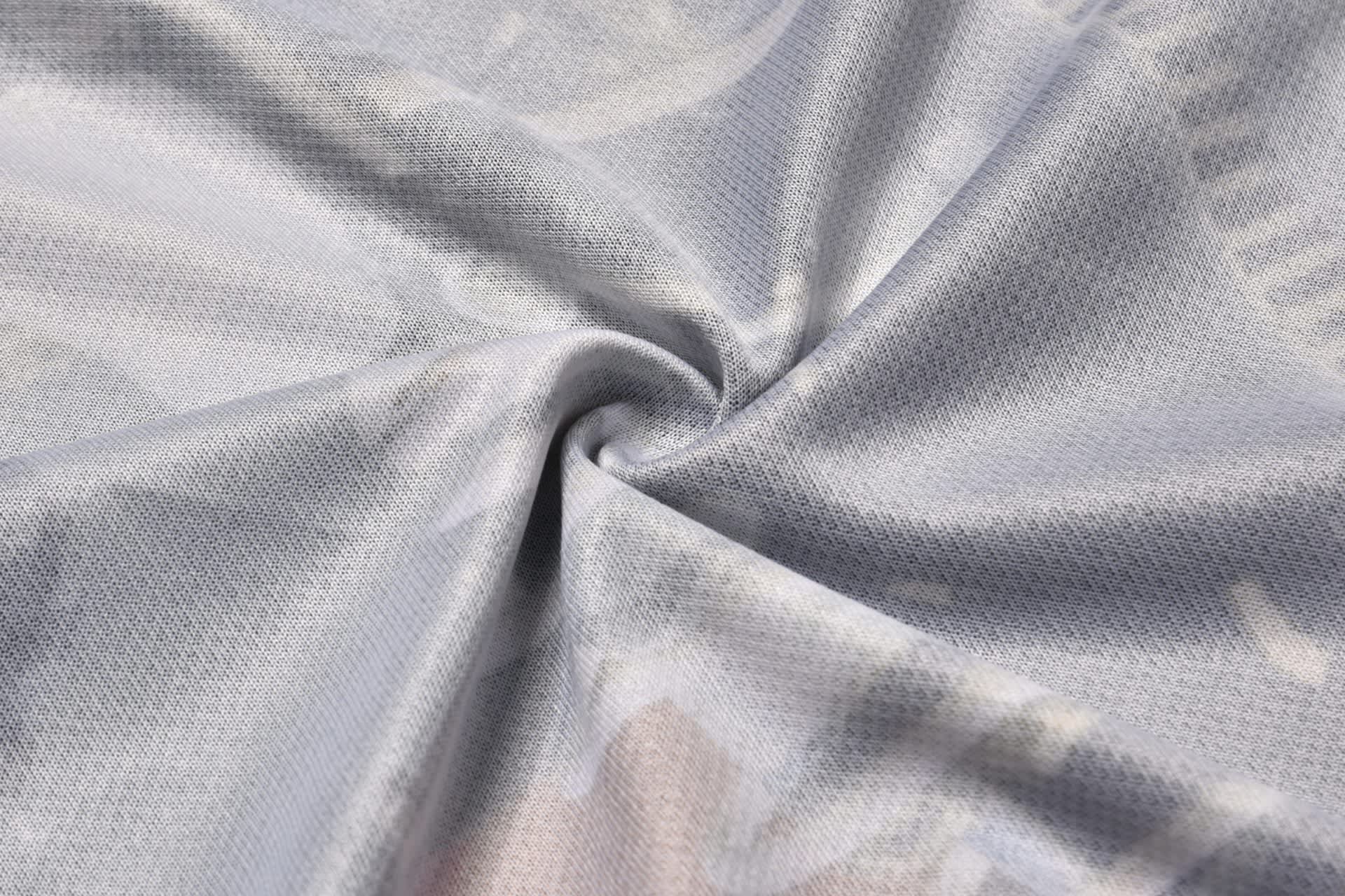 A close-up of light grey fabric with a smooth texture, featuring a subtle, patterned design and a logo.
