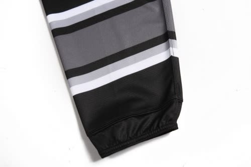 A close-up of an ice hockey racing suit featuring black, grey, and white stripes, with a snug-fitting cuff.