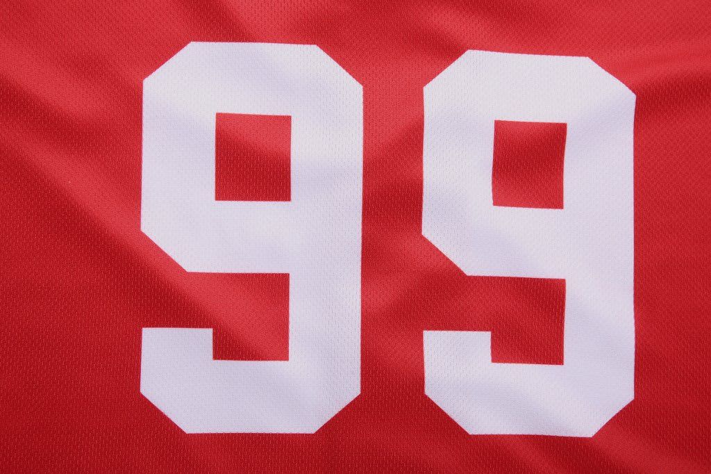 A red baseball full button tee featuring large white numbers '99'. The fabric is breathable and textured.