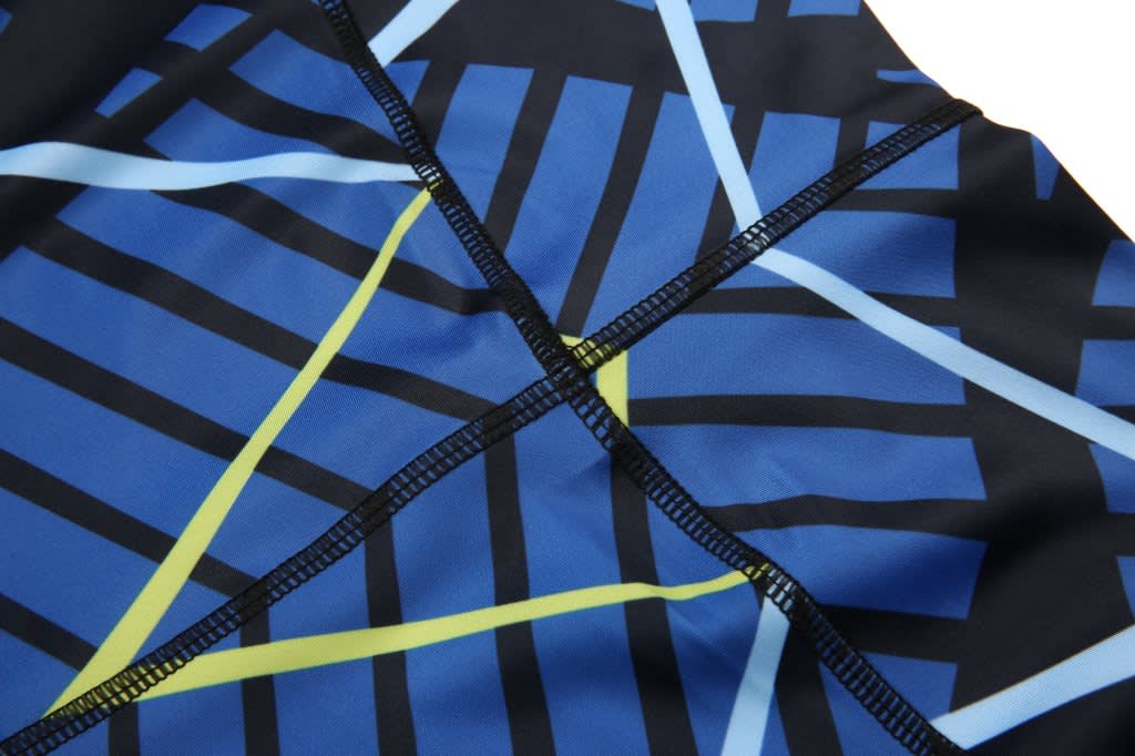 A close-up of blue leggings featuring a geometric design with black, yellow, and light blue lines, including visible stitching.