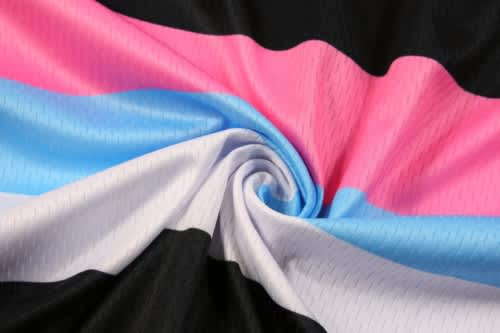 A close-up of a fabric featuring black, white, pink, and blue stripes, showcasing its texture and design.