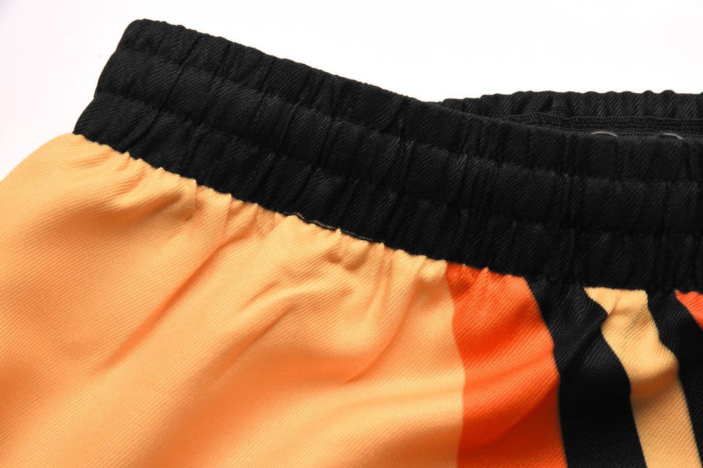 Twill rugby shorts in orange and black with an elastic waistband and a logo on the waistband.