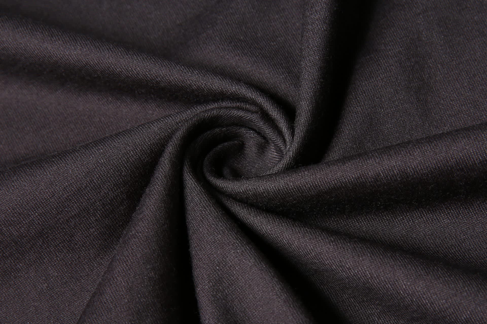 A black fabric with a smooth texture, arranged in a spiral to showcase its quality and depth.