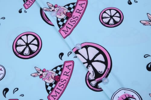 A light blue shirt featuring pink and black graphics, including a bunny, lemons, and a logo.