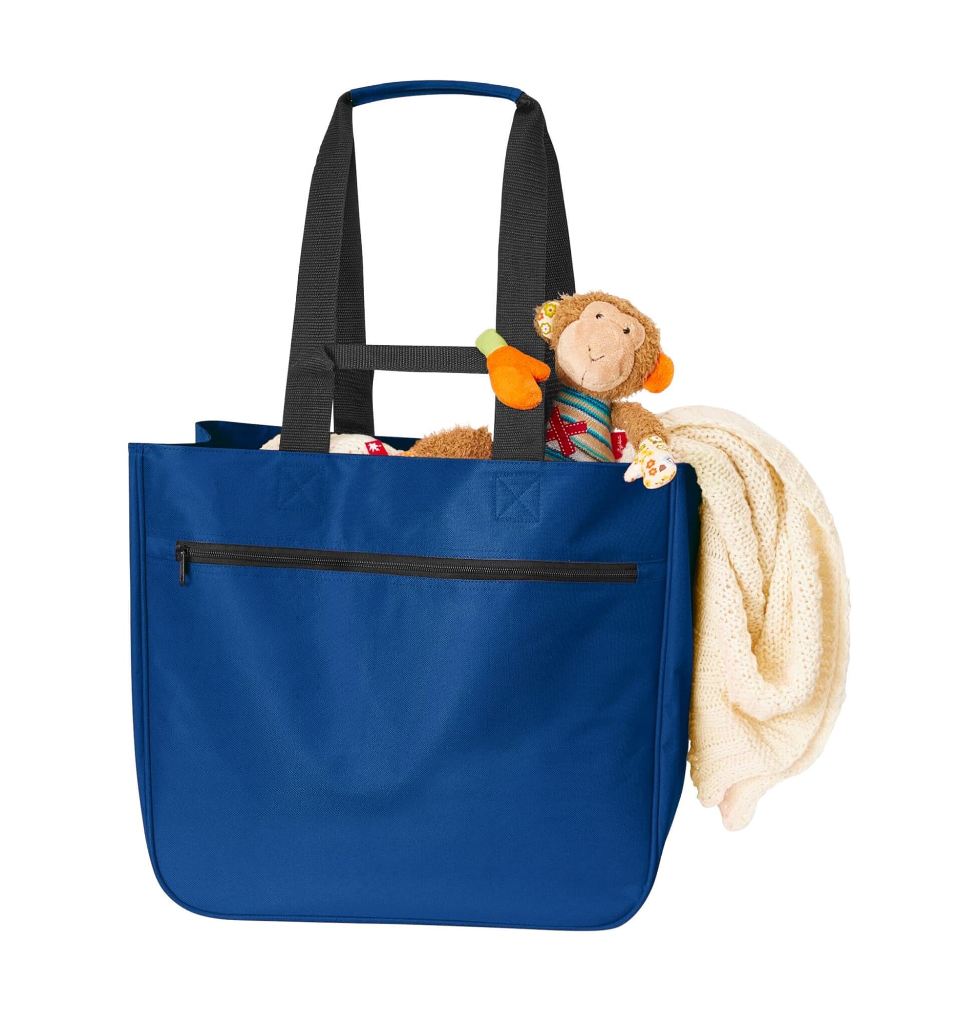 A blue tote bag with black straps, filled with a plush monkey toy and a cream-coloured blanket.