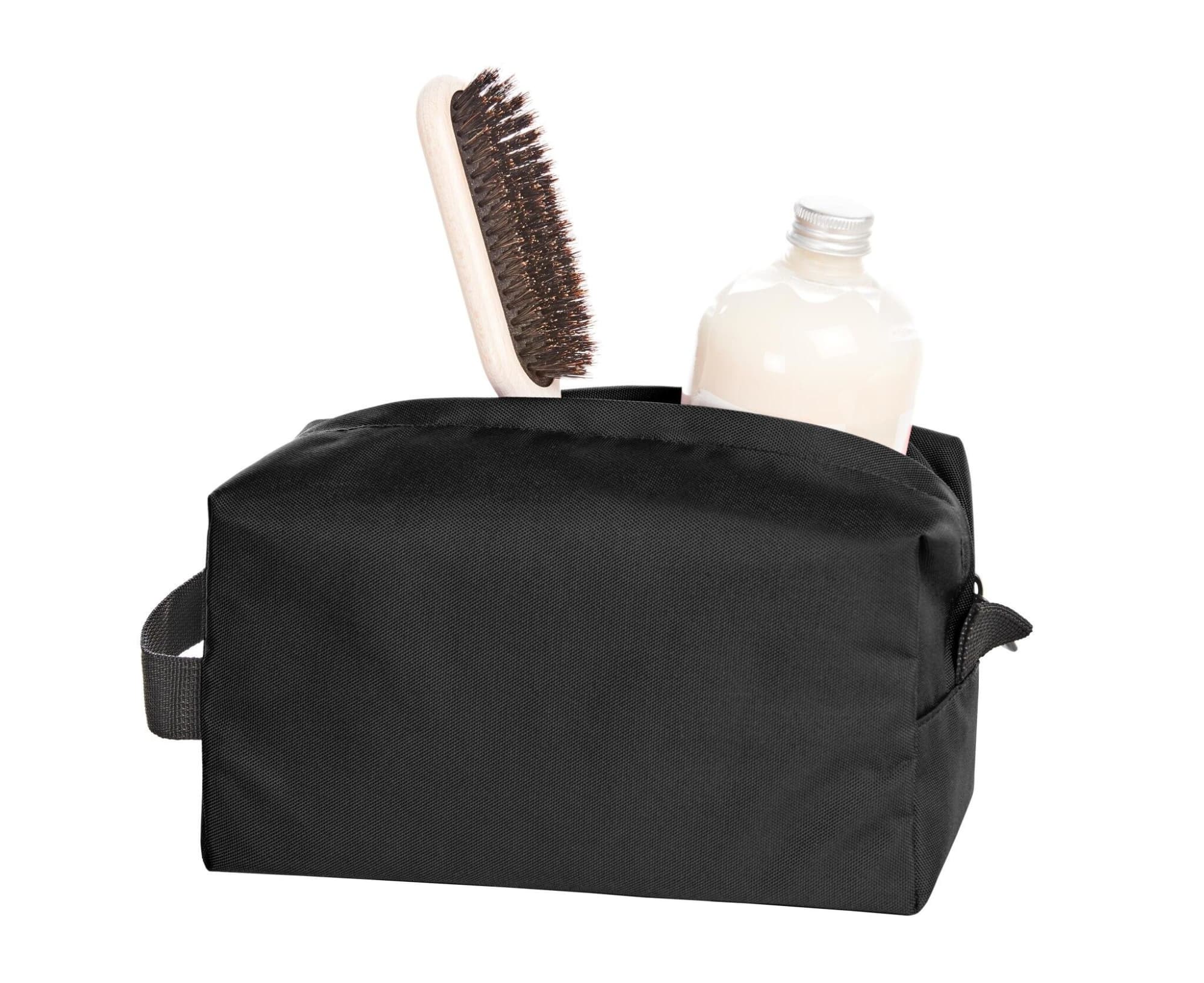 A black toiletry bag with a bottle and a hairbrush inside. Includes a handle for easy carrying.