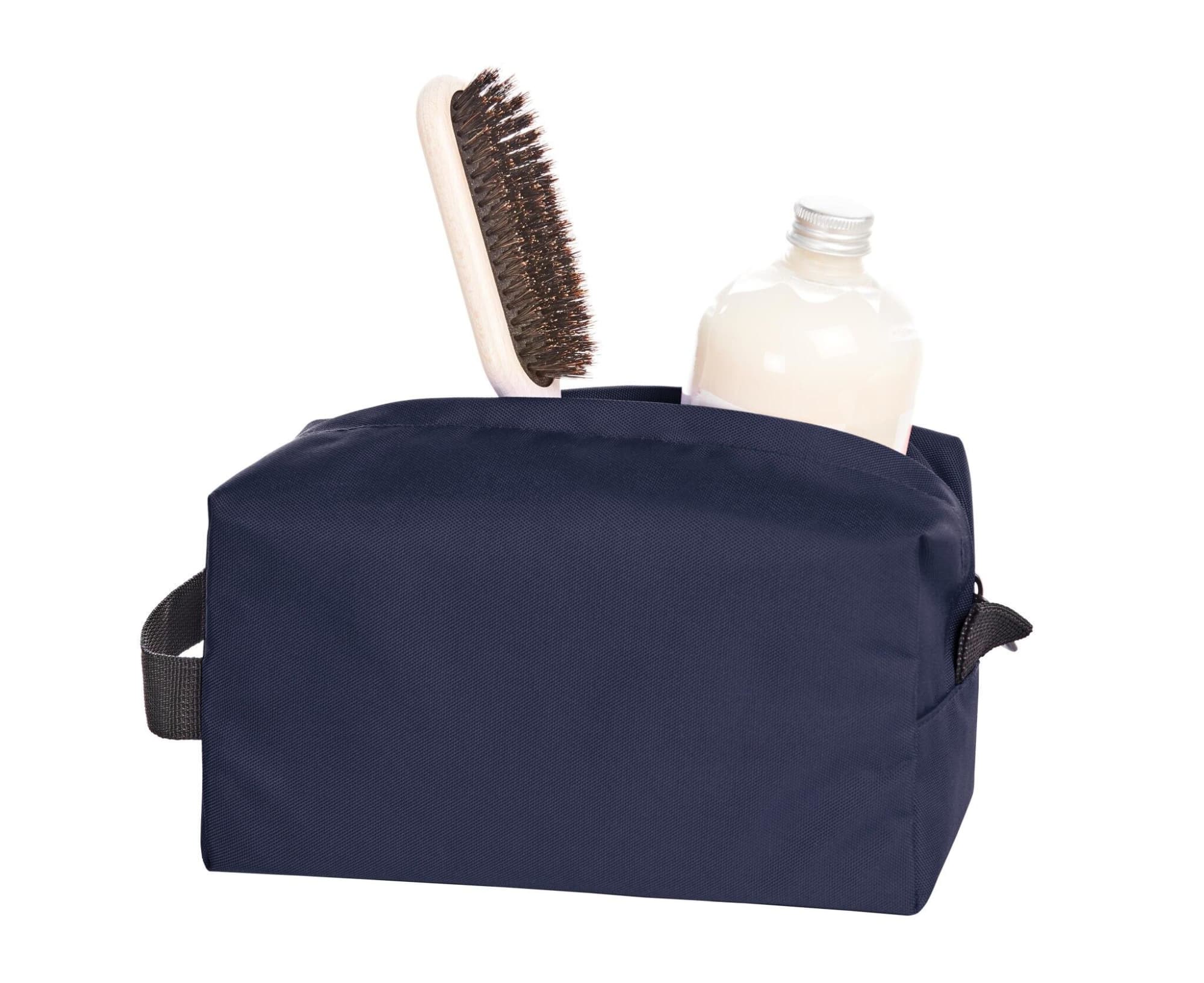 A navy toiletry bag containing a bottle and a hairbrush, featuring a branding logo.