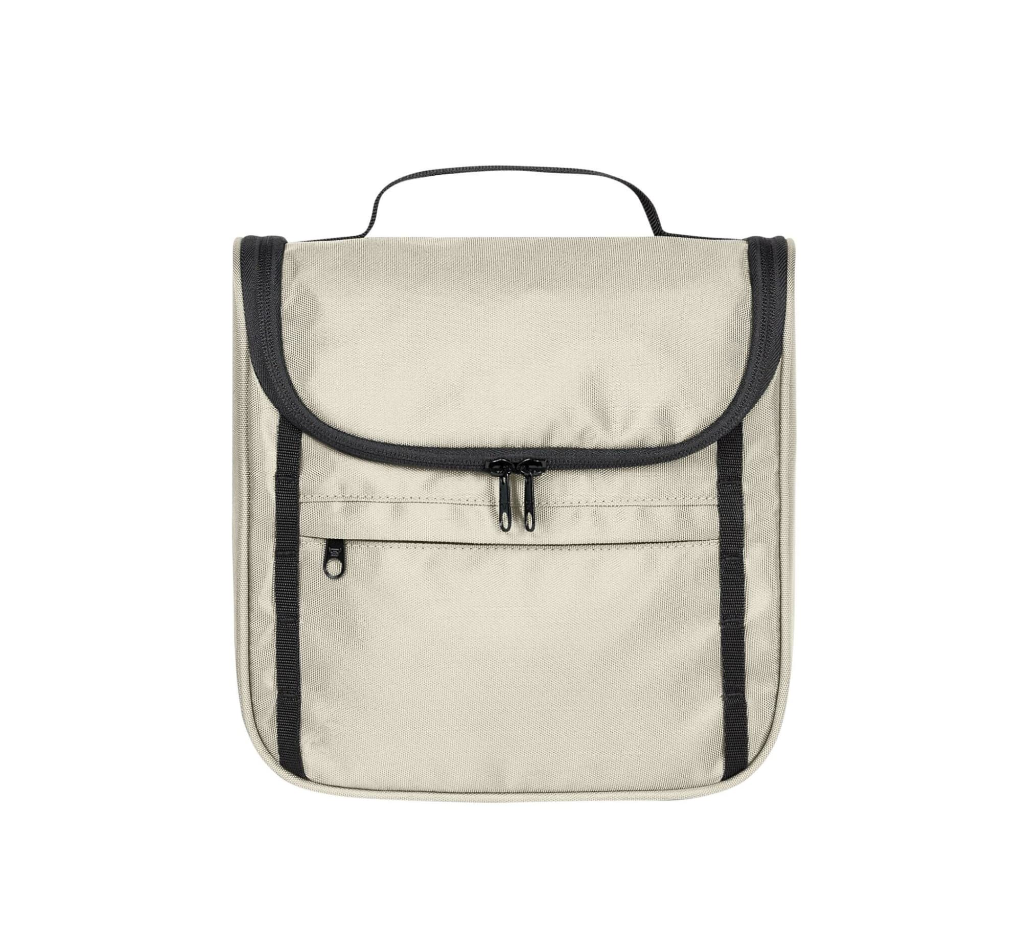 A light beige toiletry bag with a flap, black trim, and zippered pockets. It has a handle for easy carrying.