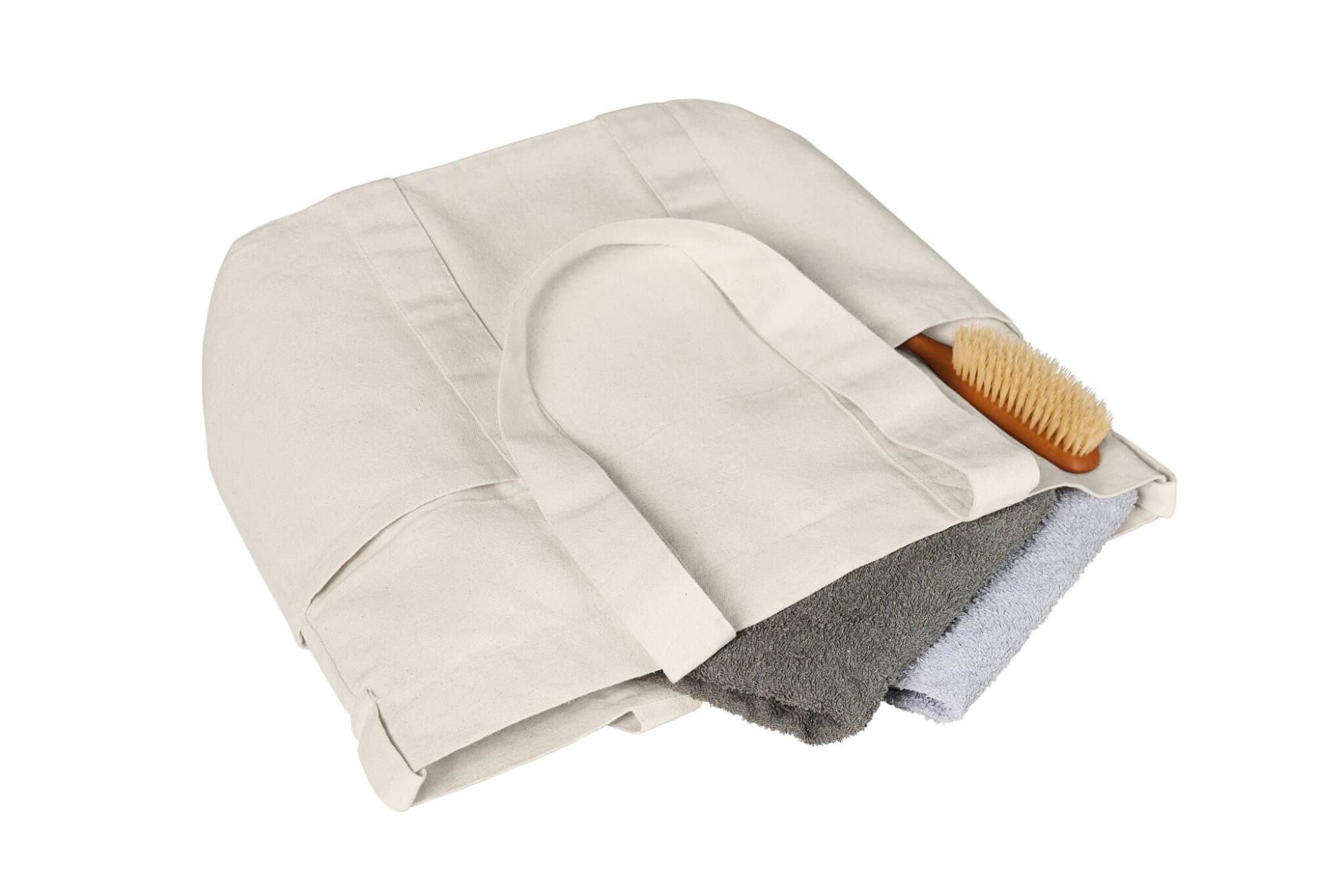 A beige tote bag filled with a grey towel and a small wooden brush, featuring a logo.