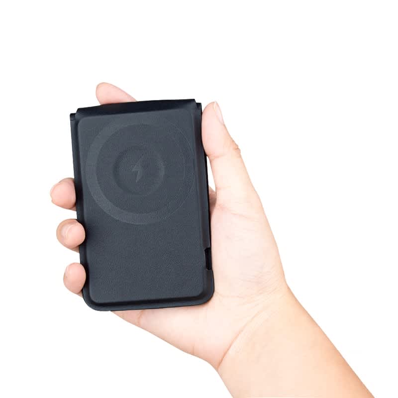 A black magnetic card wallet and wireless charging stand held in a hand. It features a logo on the surface.