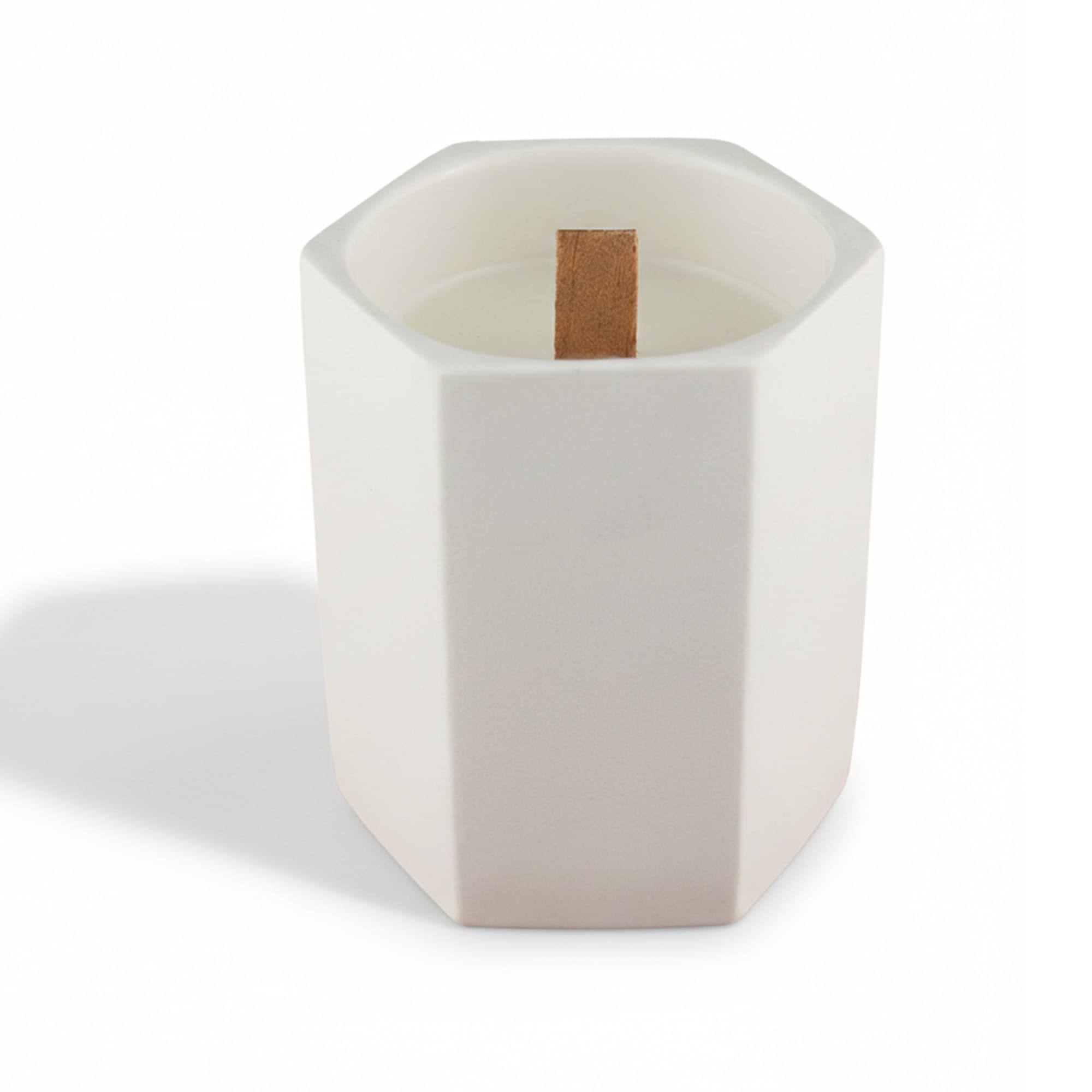 A white hexagonal ceramic candle with a wooden wick placed inside. It has a minimalist design.