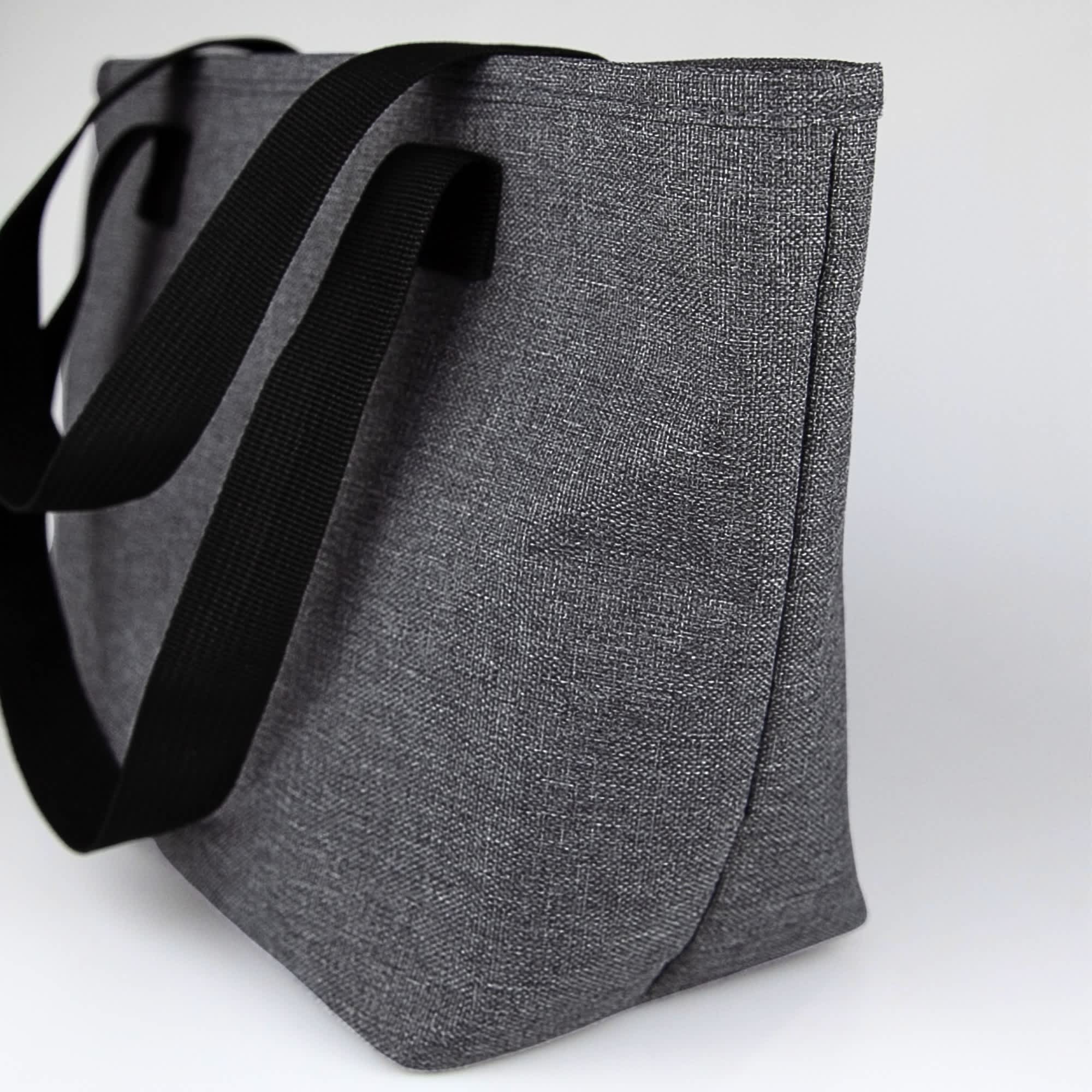 A grey lunch bag with black straps, featuring a simple design and an external logo.