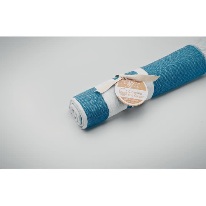A rolled-up beach towel in blue and white, secured with a ribbon and a tag. Featuring a logo on the tag.