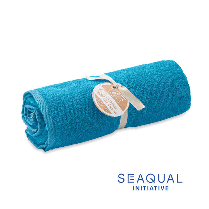 A rolled blue towel secured with a ribbon and tag, featuring a logo on the side.