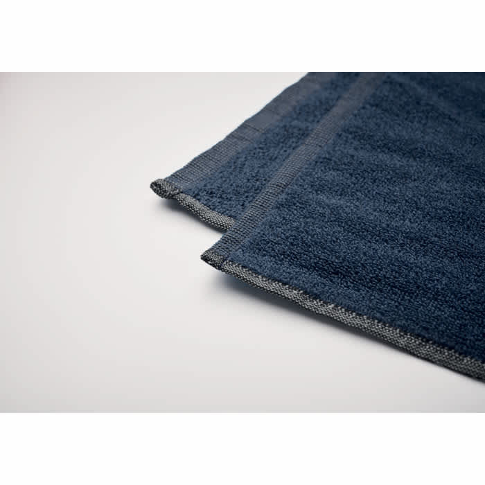 A dark blue towel with grey trim, featuring a soft texture and neat stitching at the edges.