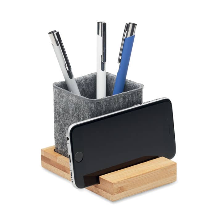 A desk organiser featuring a grey felt cup for pens and a wooden base holding a smartphone.